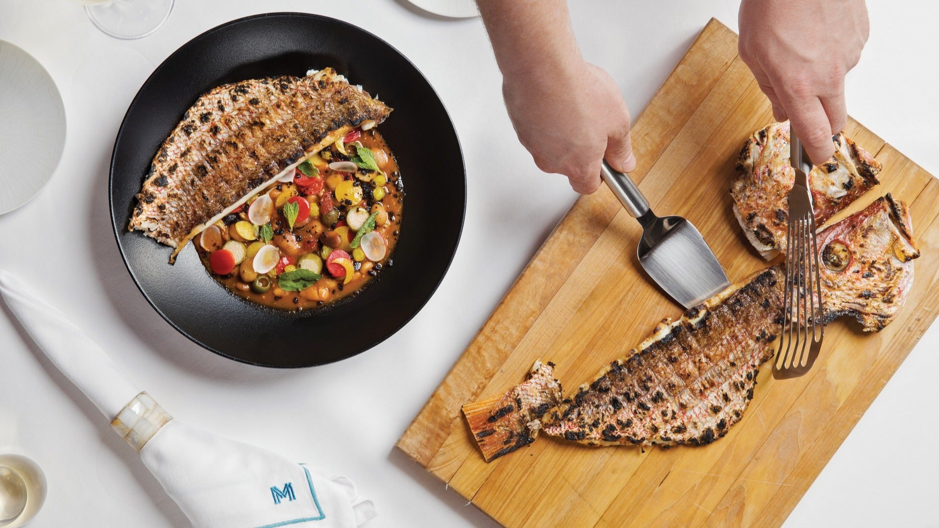 fish steak being cut and served on a plate